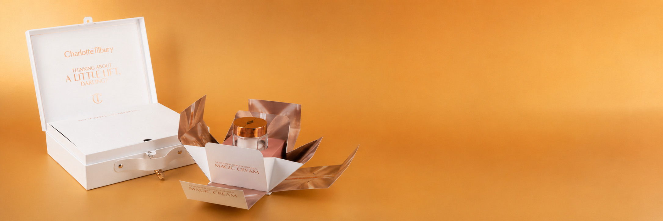 Charlotte Tilbury Magic Cream jar with a rose gold lid, displayed in open presentation packaging on an orange background