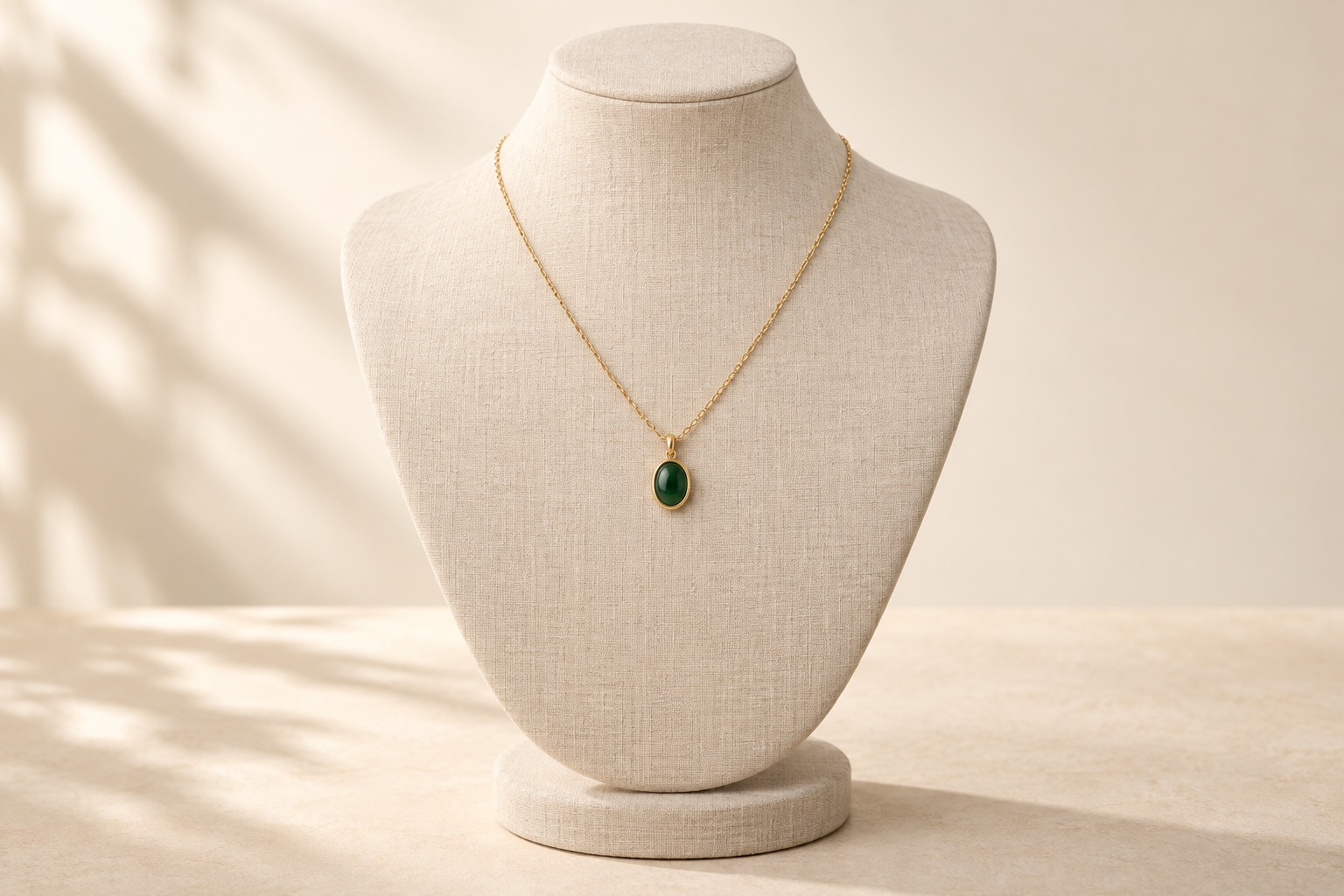 AI-created green stone pendant on a fine gold chain displayed on a cream linen jewellery bust