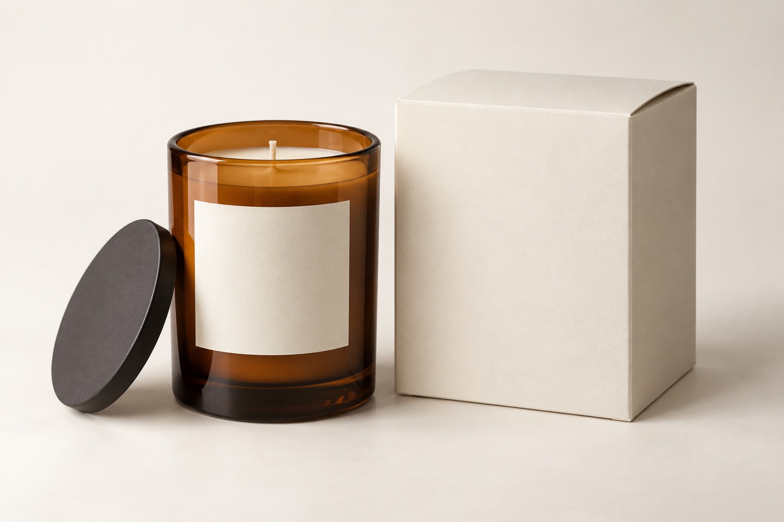 AI-created amber candle with dark lid beside a plain ivory carton on a warm white background