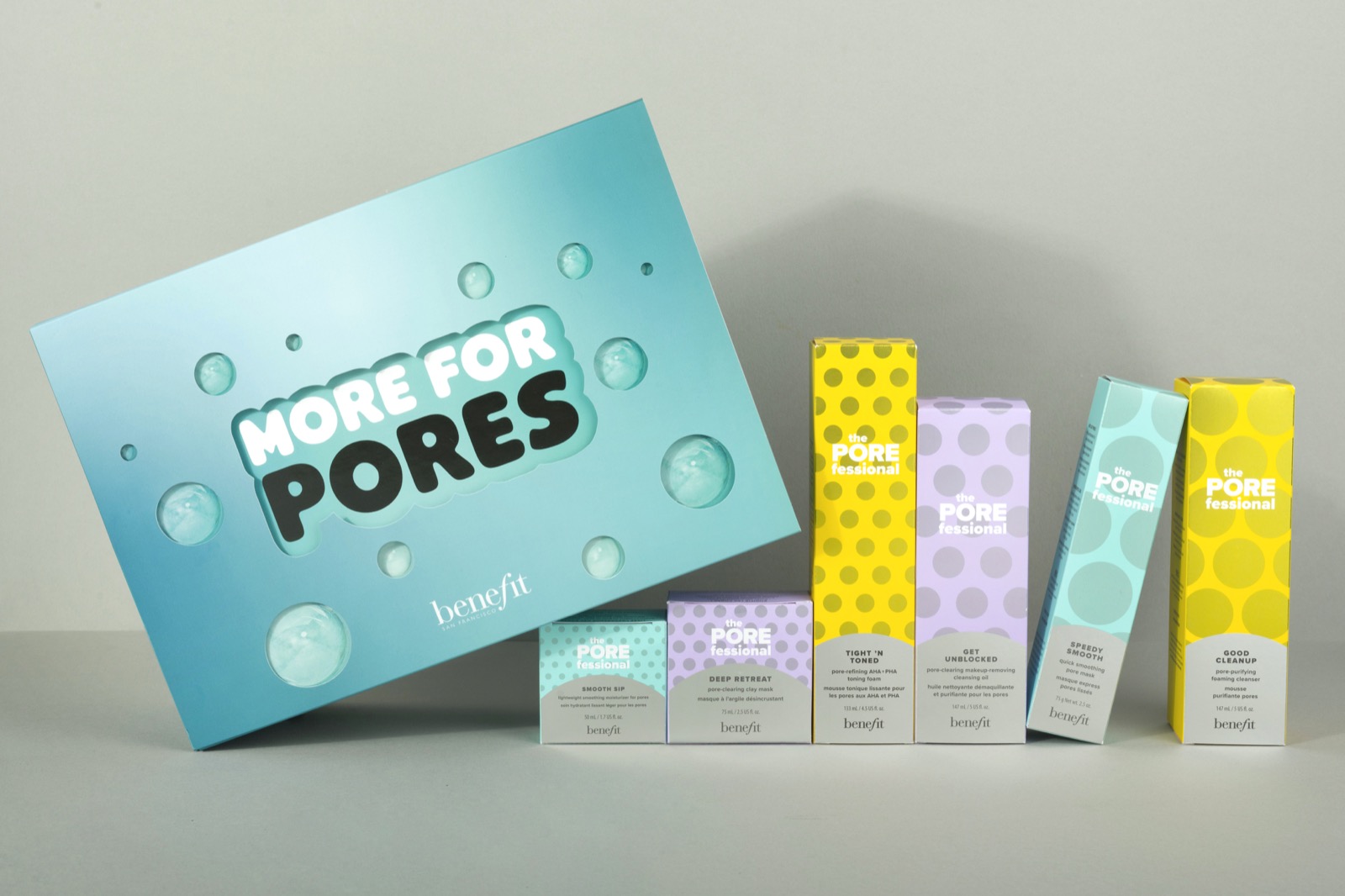 Benefit skincare collection with turquoise presentation box and yellow, lilac and mint packaging on a pale background