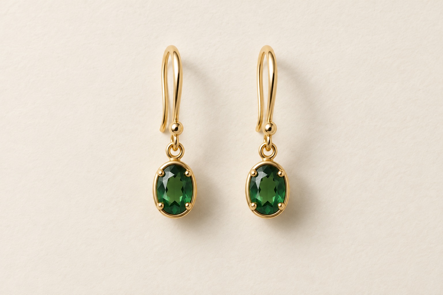 AI-created matching gold drop earrings with green oval gemstones on an off-white background